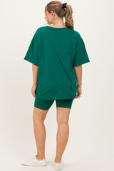 woman wearing a green oversized t-shirt and green biker shorts as maternity wear, showing her baby bump from the back