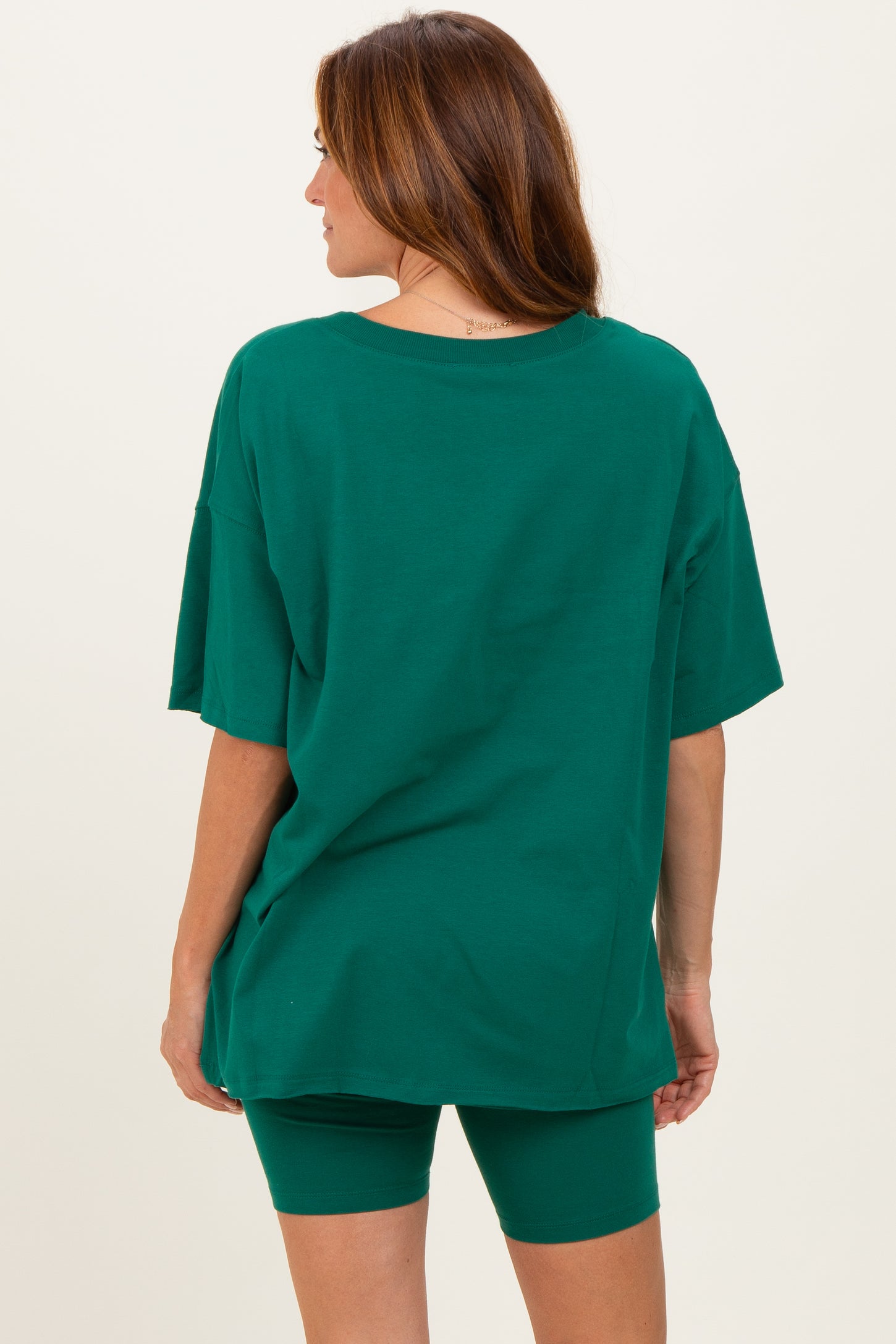 woman wearing an oversized green t-shirt and matching green bike shorts, viewed from the back