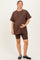 woman wearing a brown maternity oversized t-shirt and matching bike shorts, showcasing her baby bump