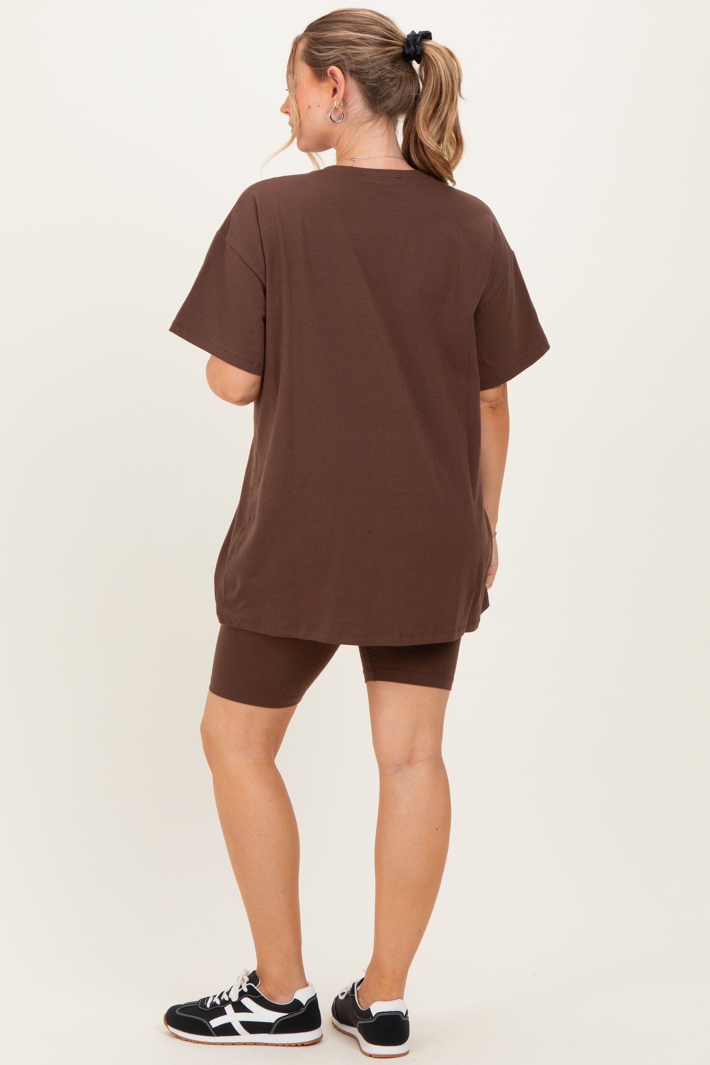 woman wearing a brown oversized t-shirt and matching bike shorts, showcasing comfortable maternity wear