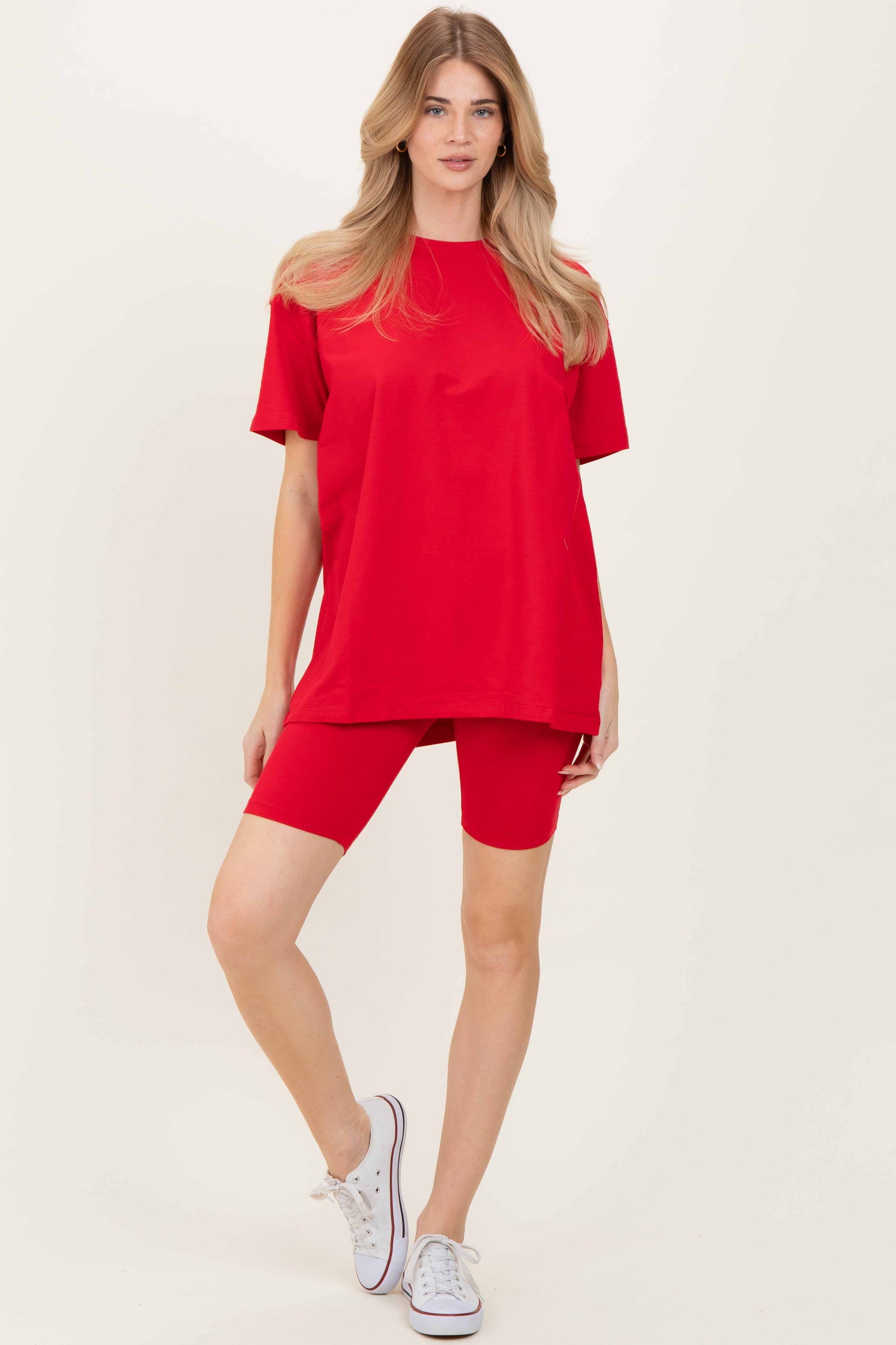 woman wearing a bright red oversized t-shirt and matching red bike shorts with white sneakers