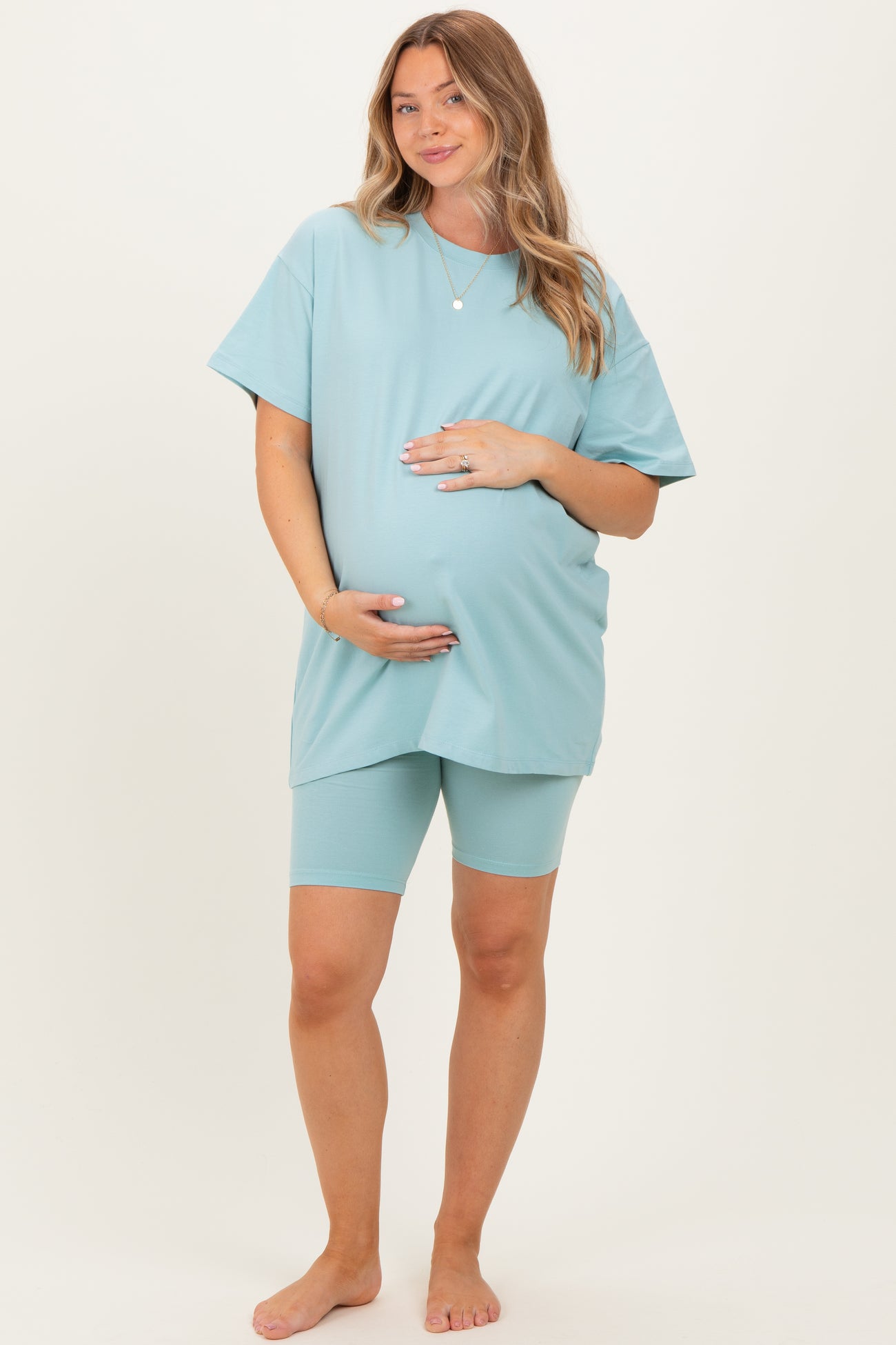 woman wearing a light blue maternity t-shirt and matching shorts, showing off her baby bump