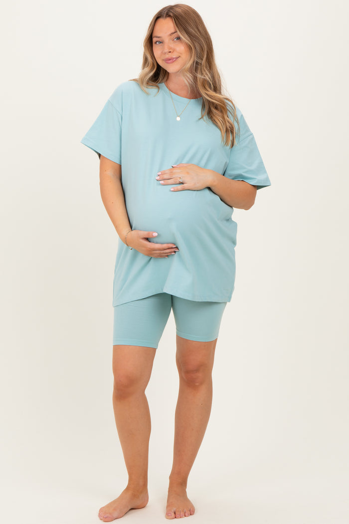woman wearing a light blue maternity t-shirt and matching shorts, showing off her baby bump