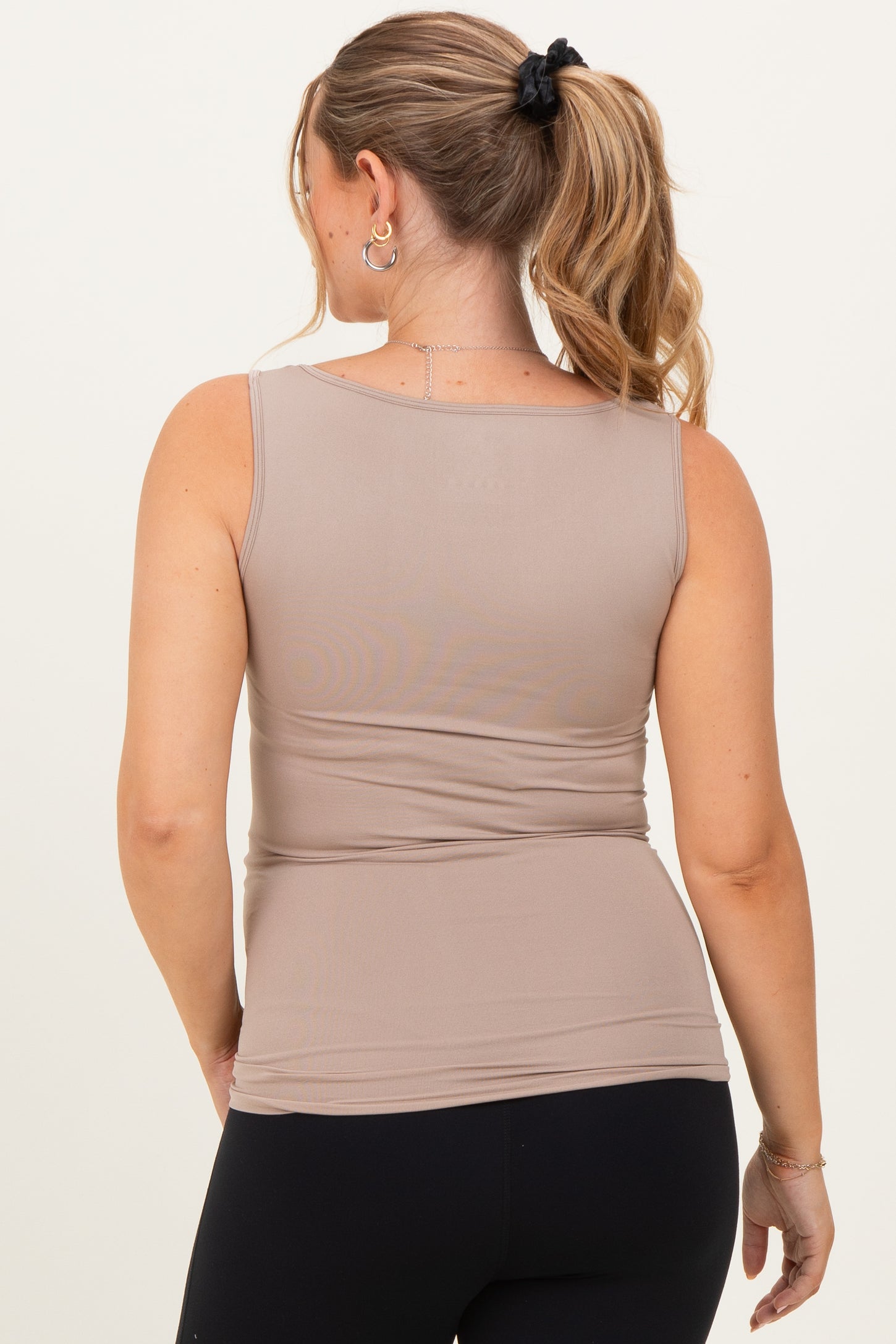 woman wearing a light brown maternity tank top, showing a pregnant belly from the back