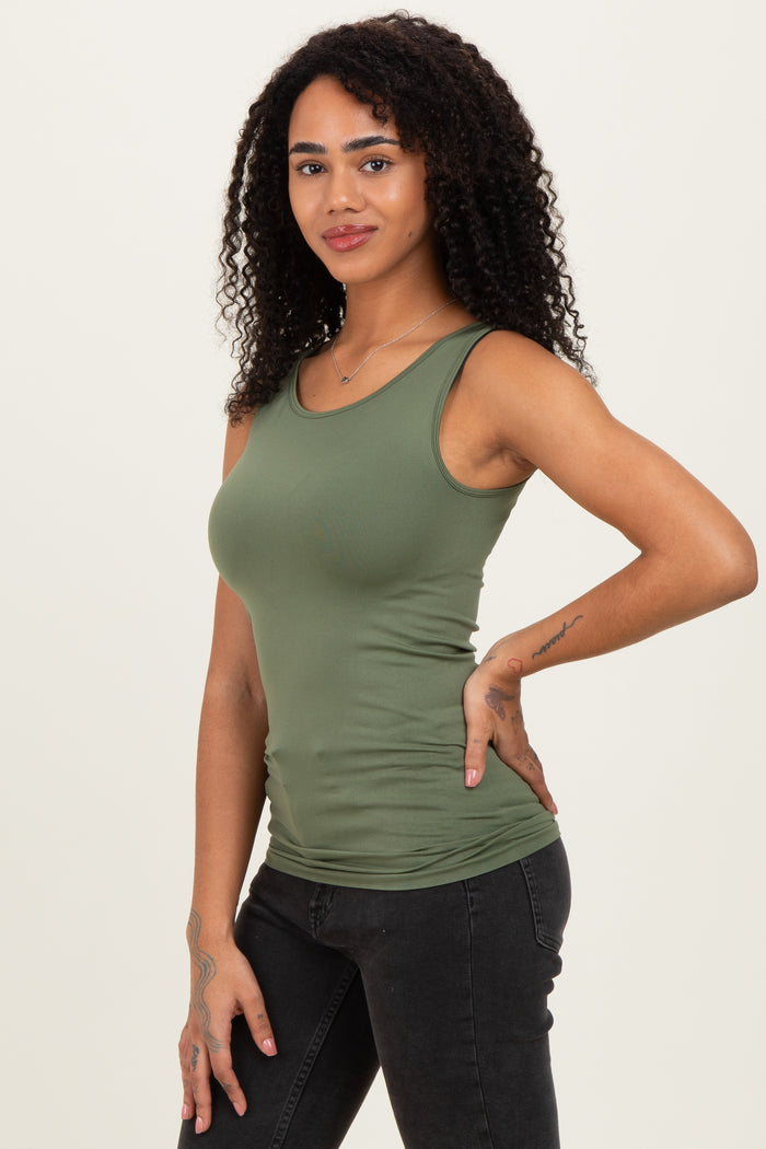 woman wearing a fitted olive green tank top and black jeans, posing with one hand on her hip