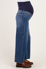 woman wearing blue wide-leg maternity jeans with a belly panel, showing her baby bump