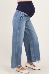 woman wearing light blue wide-leg maternity jeans with a frayed hem and a navy blue over-the-bump waistband, showing baby bump