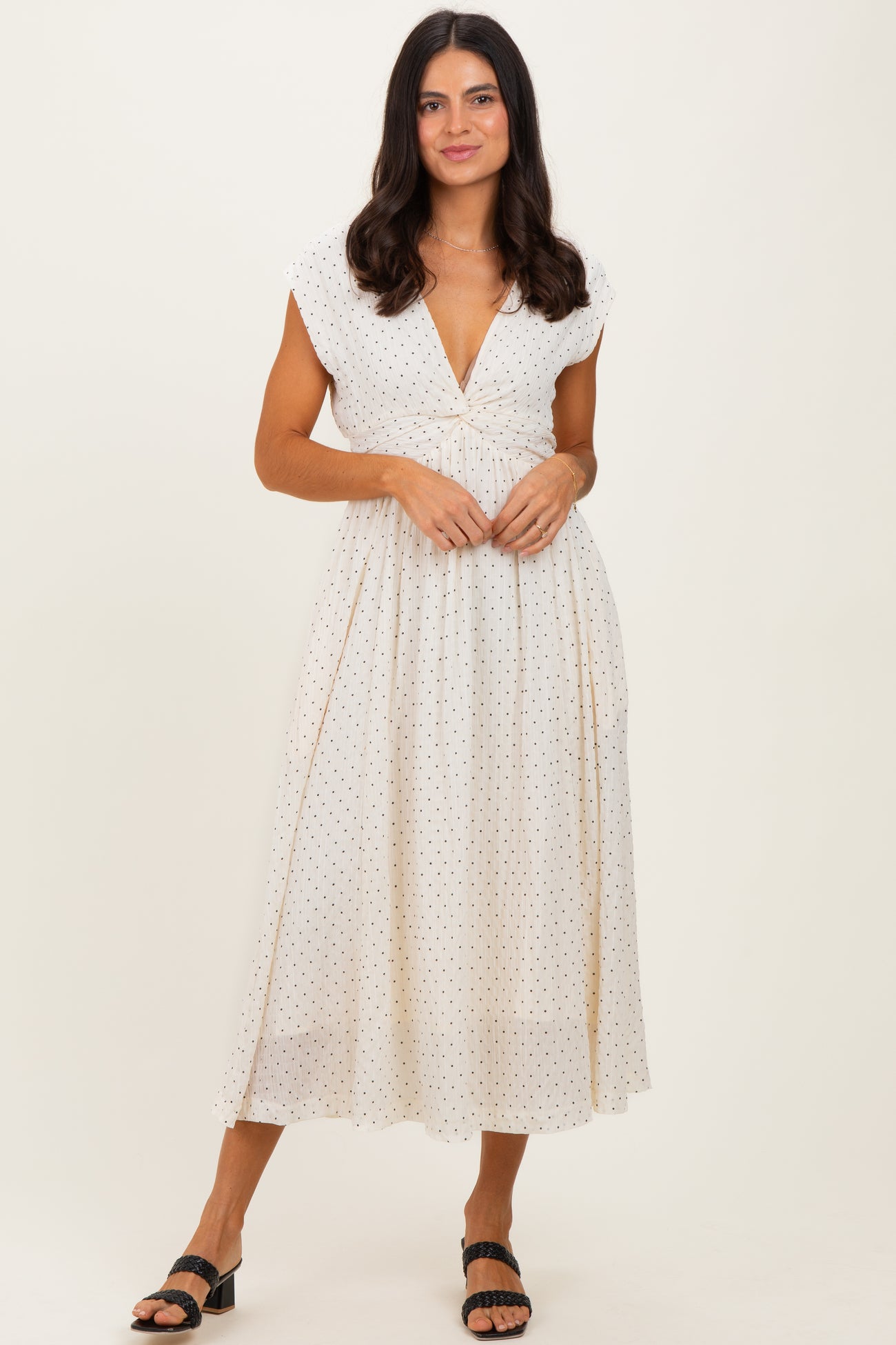 woman wearing a white polka dot midi dress with cap sleeves and a deep v-neckline
