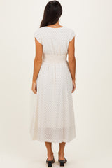 woman wearing a white midi dress with polka dots and a smocked waist, viewed from the back