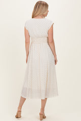 woman wearing a white midi dress with black polka dots and a smocked waist, seen from the back