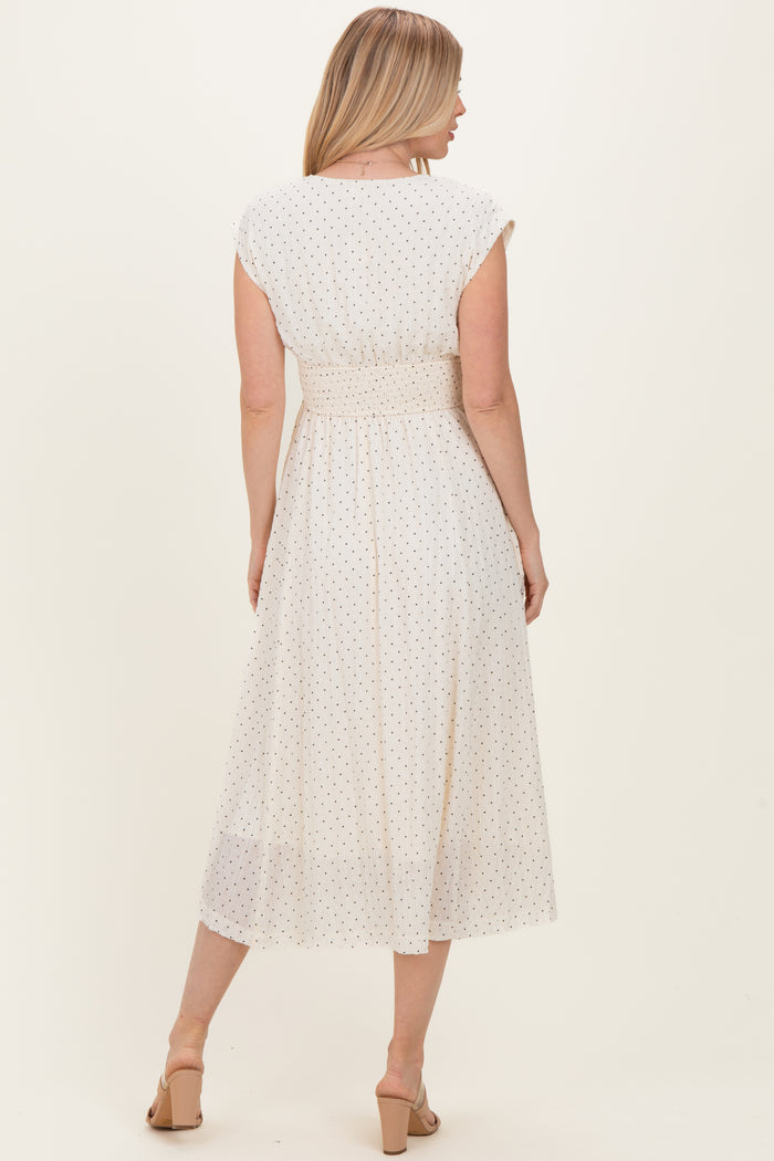 woman wearing a white midi dress with black polka dots and a smocked waist, seen from the back