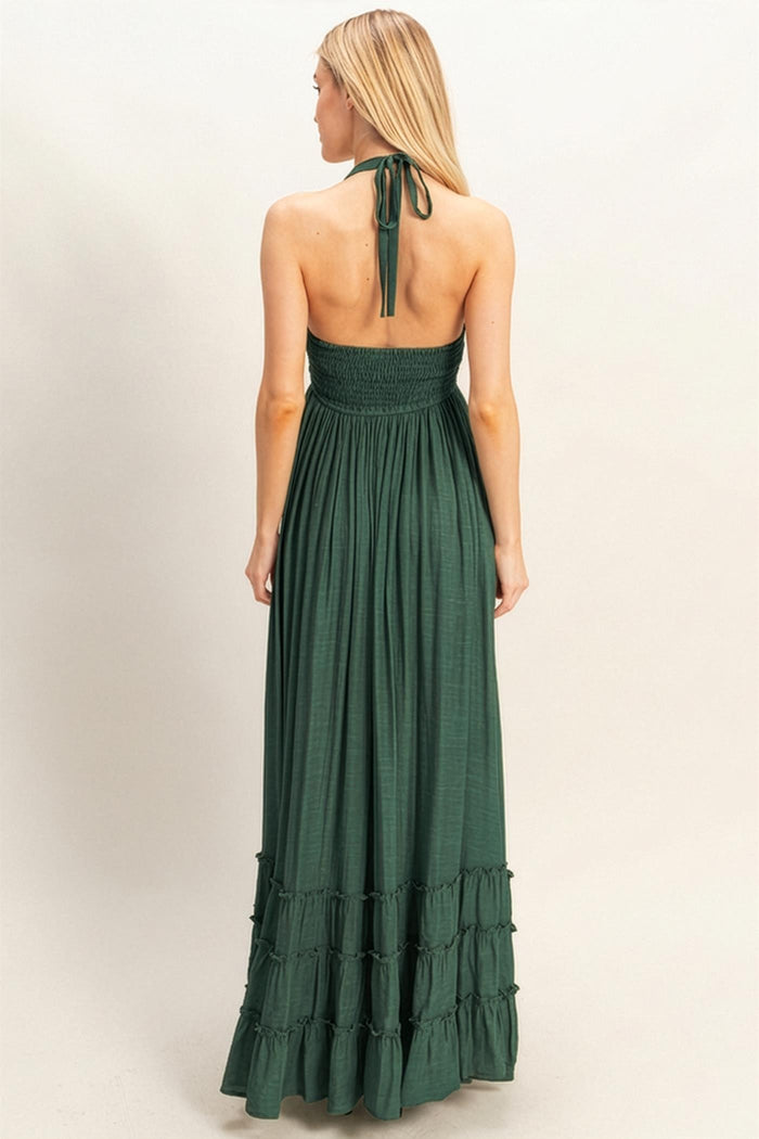 back view of a woman wearing a dark green maxi dress with a smocked bodice and tiered ruffle hem
