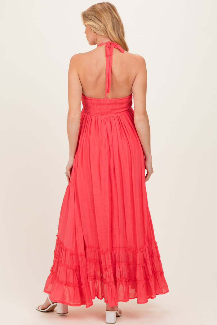 woman wearing a coral maternity maxi dress with a smocked back and ruffled hemline, showing a baby bump
