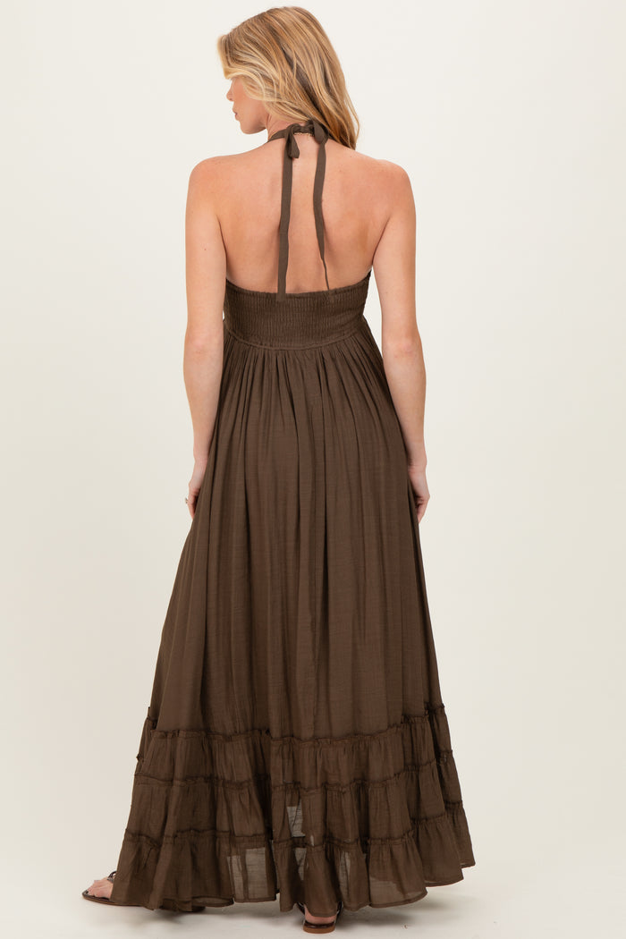 woman wearing a brown maternity maxi dress with a halter neck and ruffled hem, showing off her baby bump