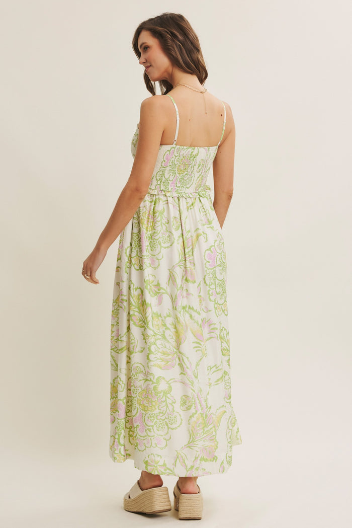 woman wearing a white maxi dress with green and pink floral print, showing the back view