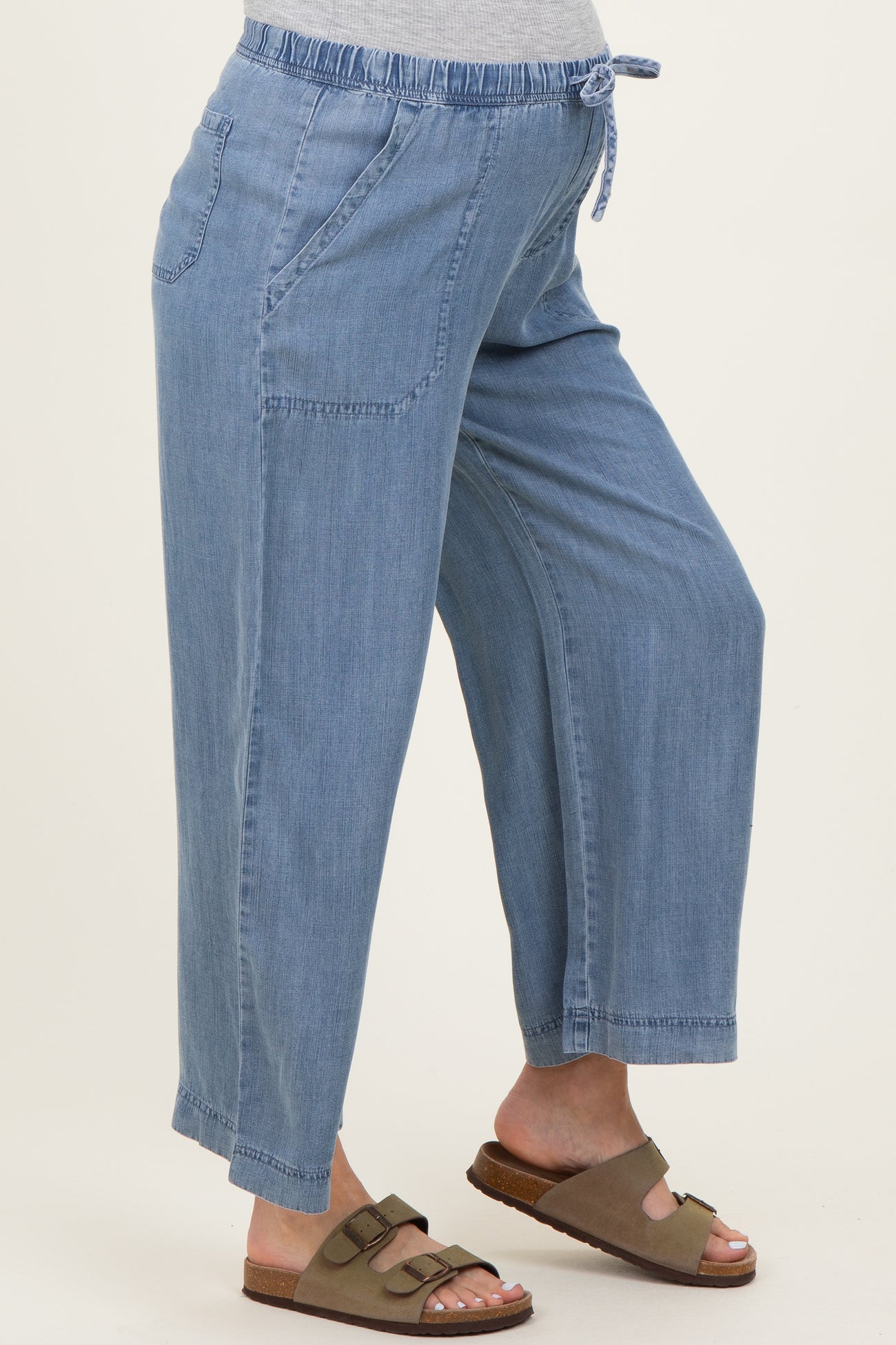 woman wearing light blue maternity pants with elastic waistband and side pockets, showcasing her baby bump