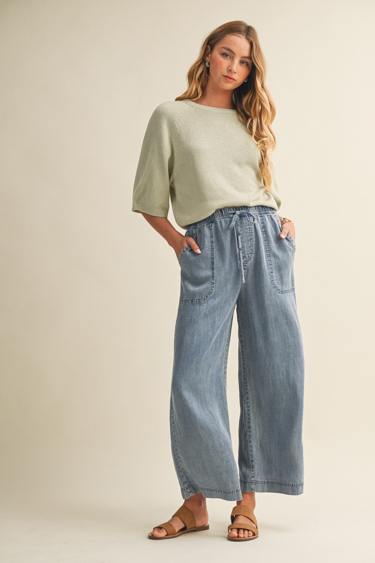 woman wearing a light green oversized sweater and wide-leg chambray pants with pockets and sandals