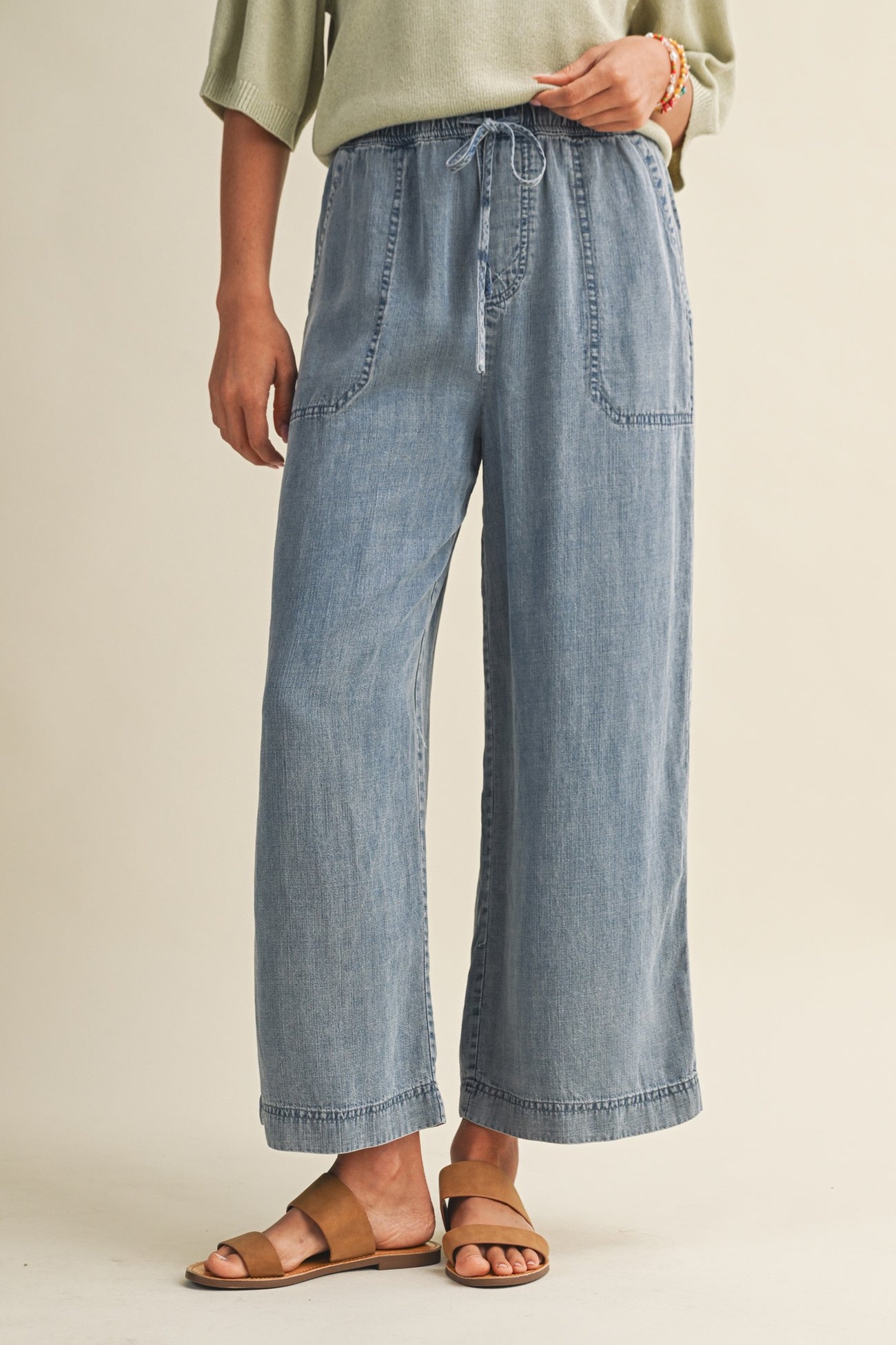 woman wearing light blue wide-leg denim pants with a drawstring waist and front pockets