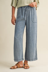woman wearing light blue wide-leg denim pants with a drawstring waist and front pockets