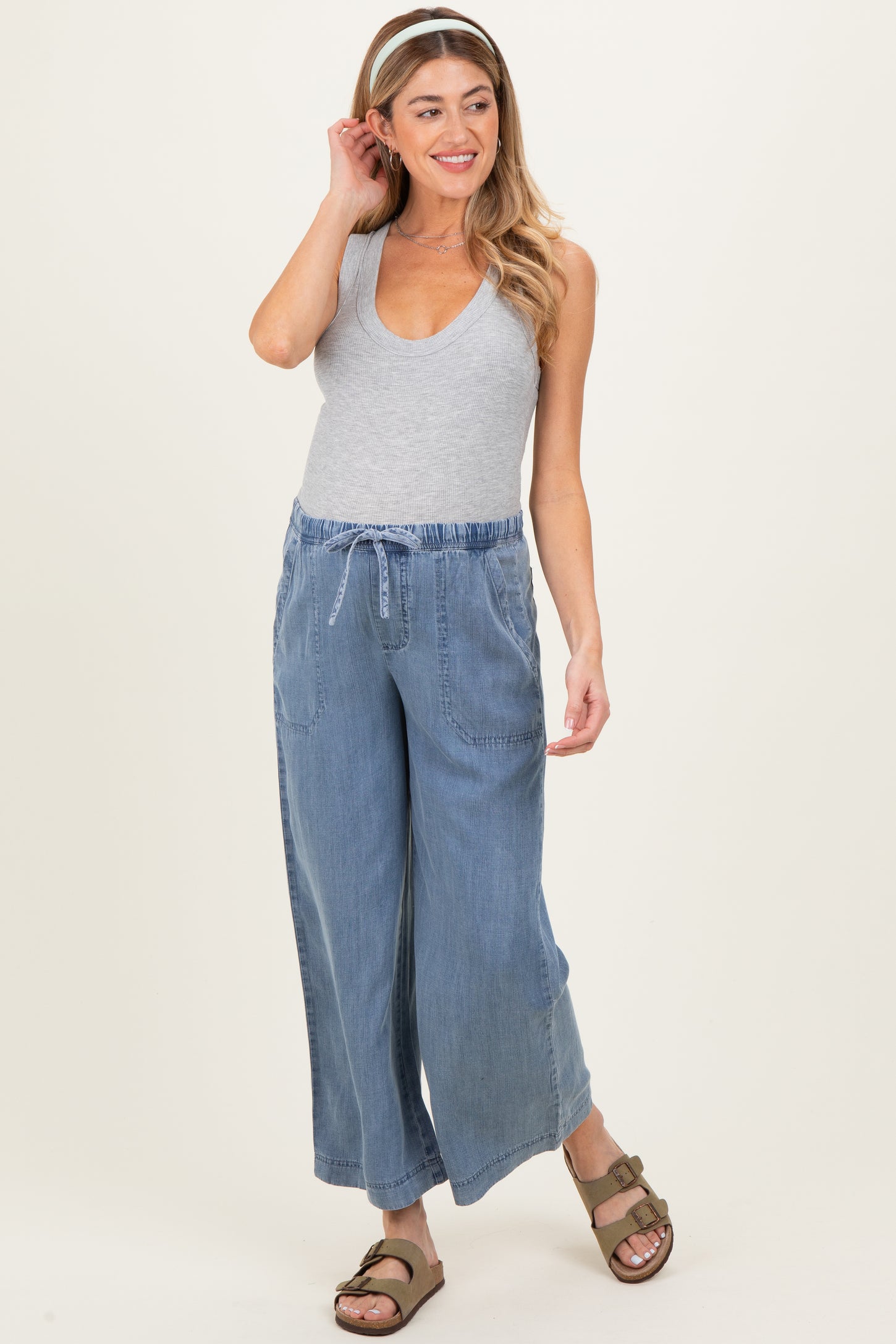 woman wearing a gray sleeveless maternity top and blue wide-leg maternity pants with an adjustable drawstring waist