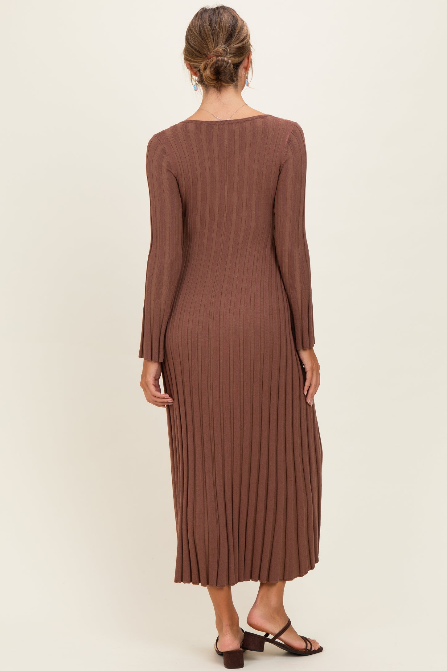 woman wearing a long brown ribbed knit dress with long sleeves and a flared hem, seen from the back