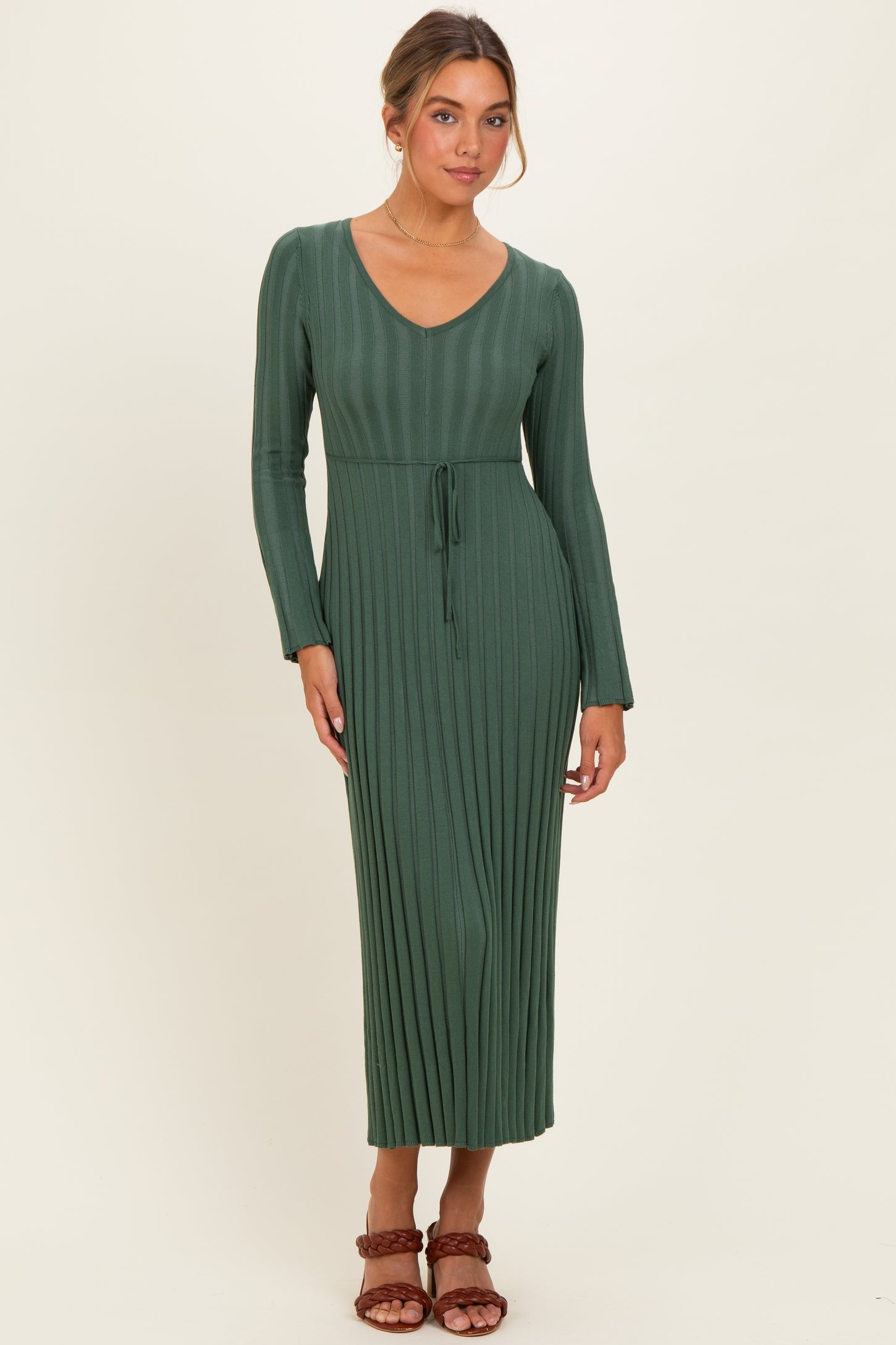 woman wearing a long green ribbed knit maxi dress with a v-neck and belt detail