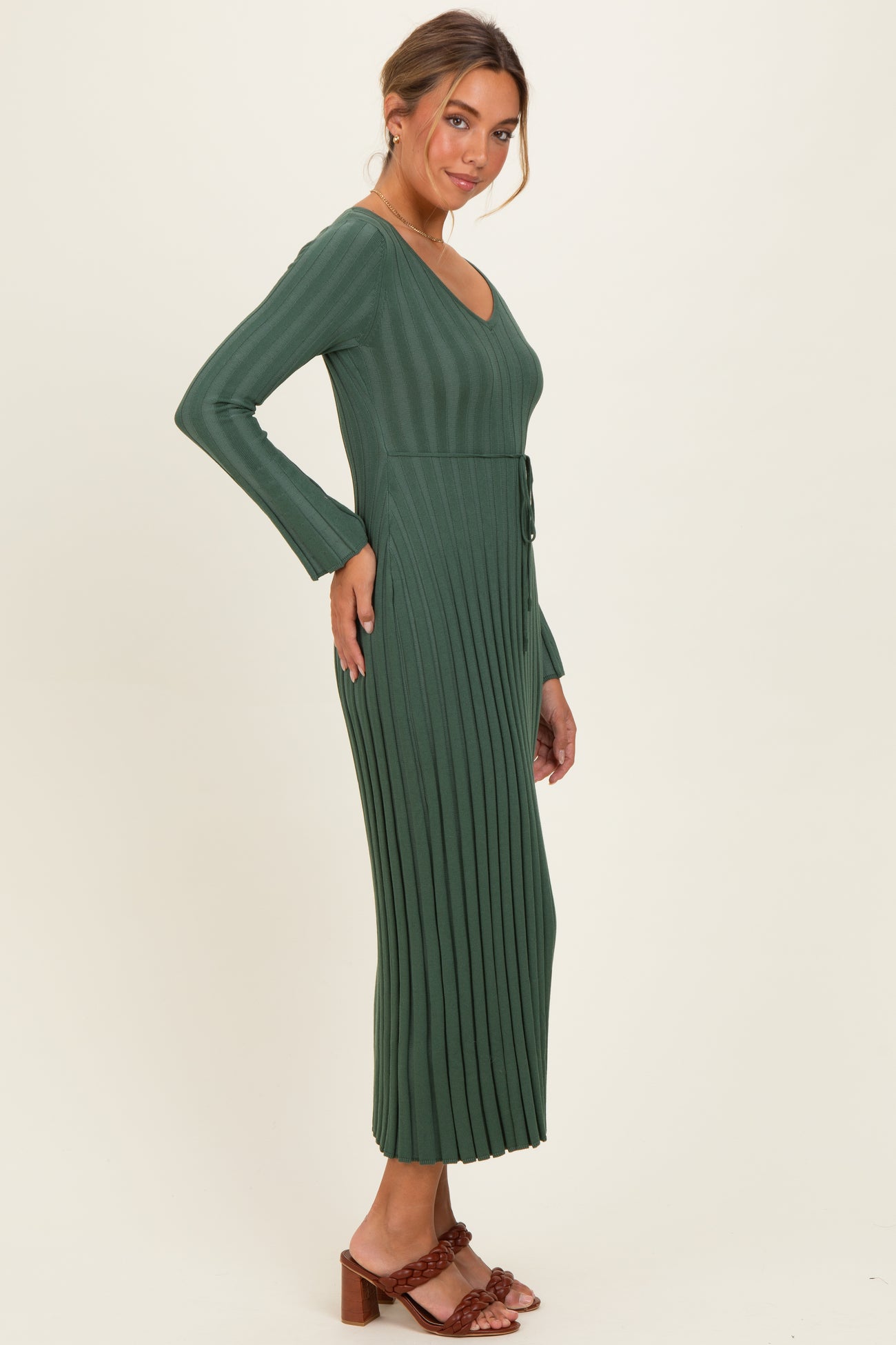 woman wearing a dark green ribbed maxi dress with long sleeves and a tied waist detail
