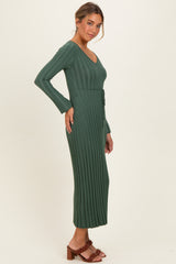 woman wearing a dark green ribbed maxi dress with long sleeves and a tied waist detail