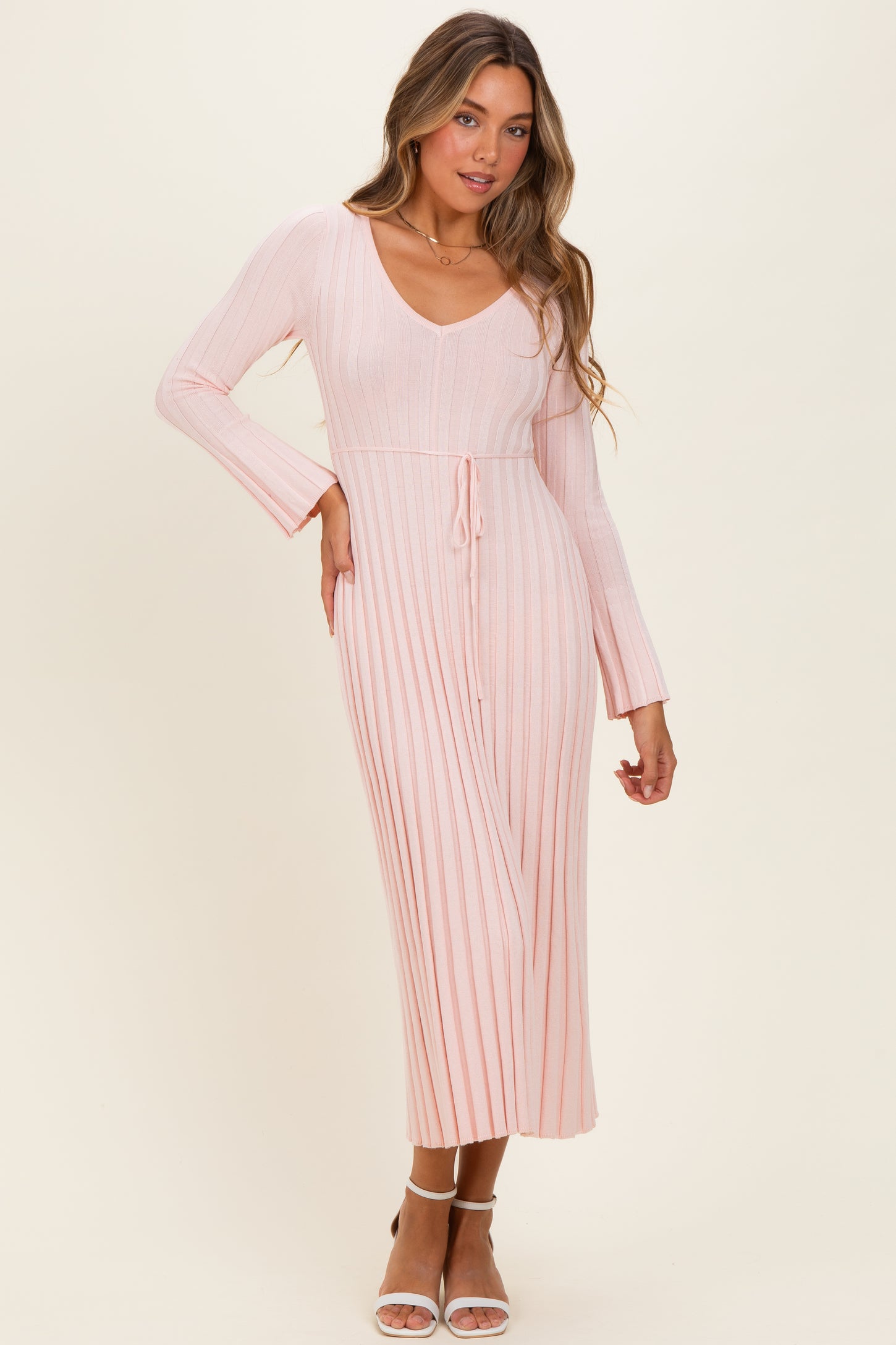 woman wearing a pink ribbed long sleeve midi dress with a v-neck and tie waist detail
