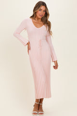 woman wearing a pink ribbed long sleeve midi dress with a v-neck and tie waist detail