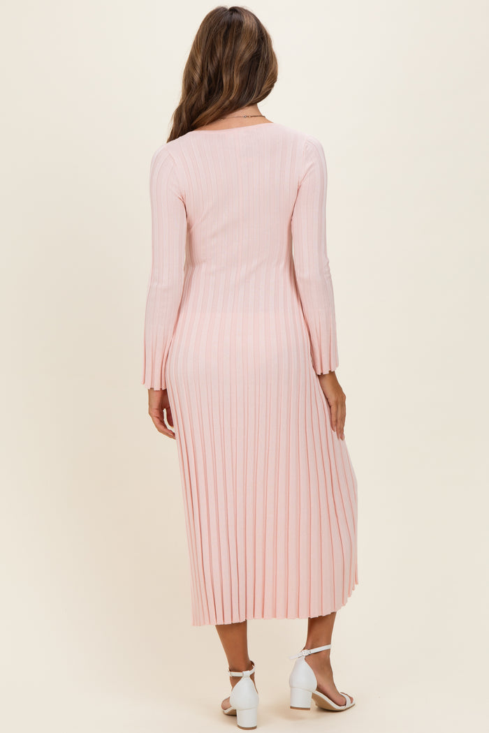 woman wearing a light pink pleated maxi dress with long sleeves, showing the back view