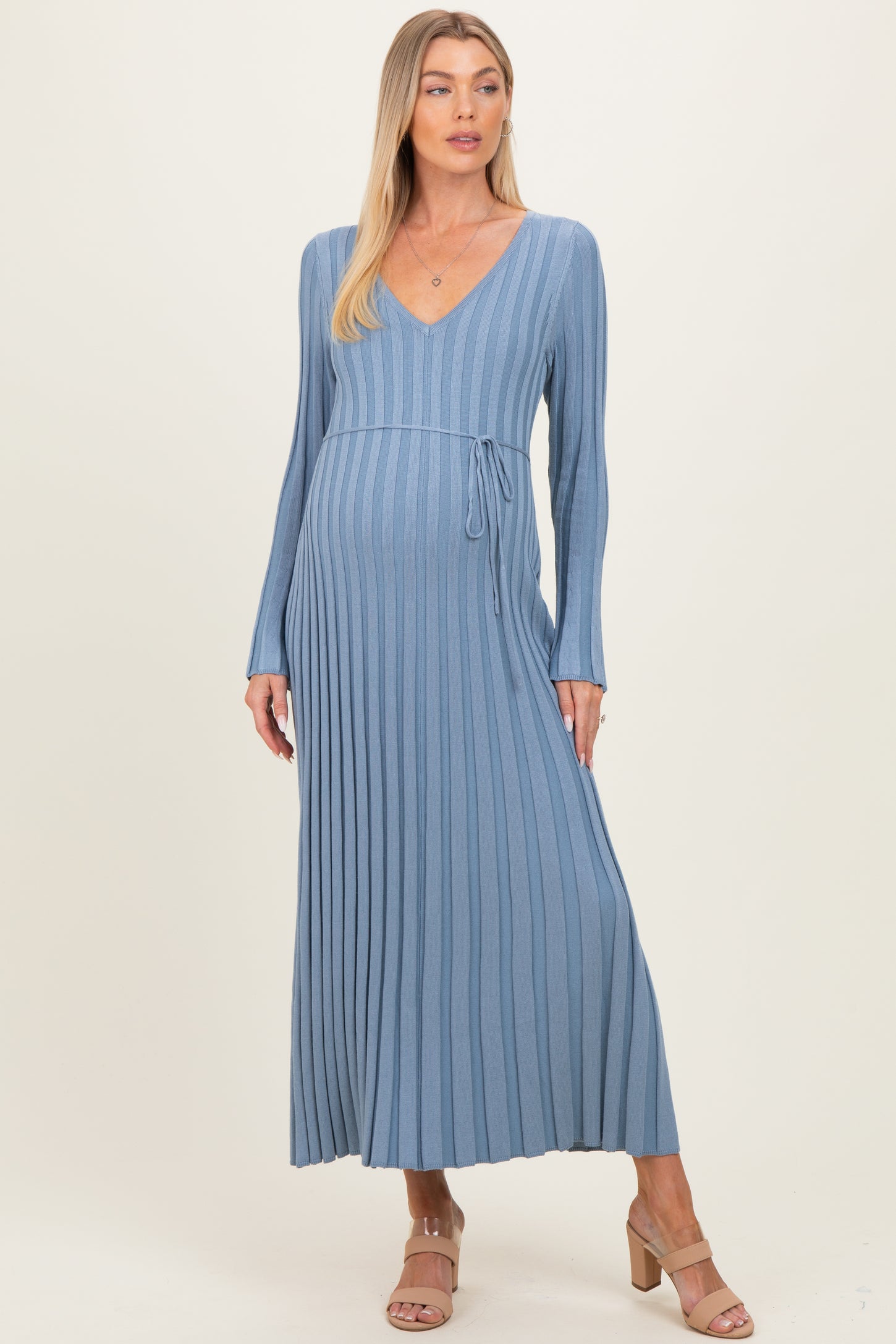 woman wearing a light blue ribbed maternity maxi dress with a v-neck and tie detail, showcasing her baby bump