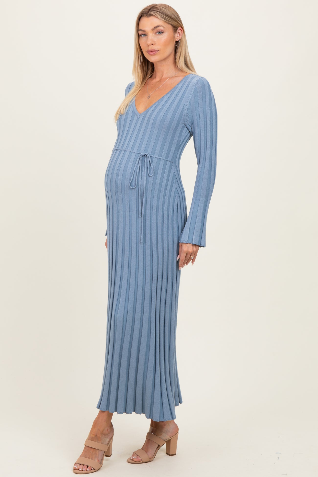 woman wearing a ribbed blue maternity dress with a v-neckline and tie waist, showing her baby bump