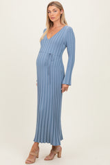 woman wearing a ribbed blue maternity dress with a v-neckline and tie waist, showing her baby bump