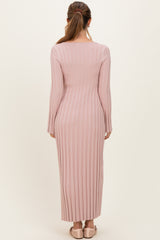 woman wearing a long pink ribbed maternity dress, showing the back view with fitted sleeves and a maxi length