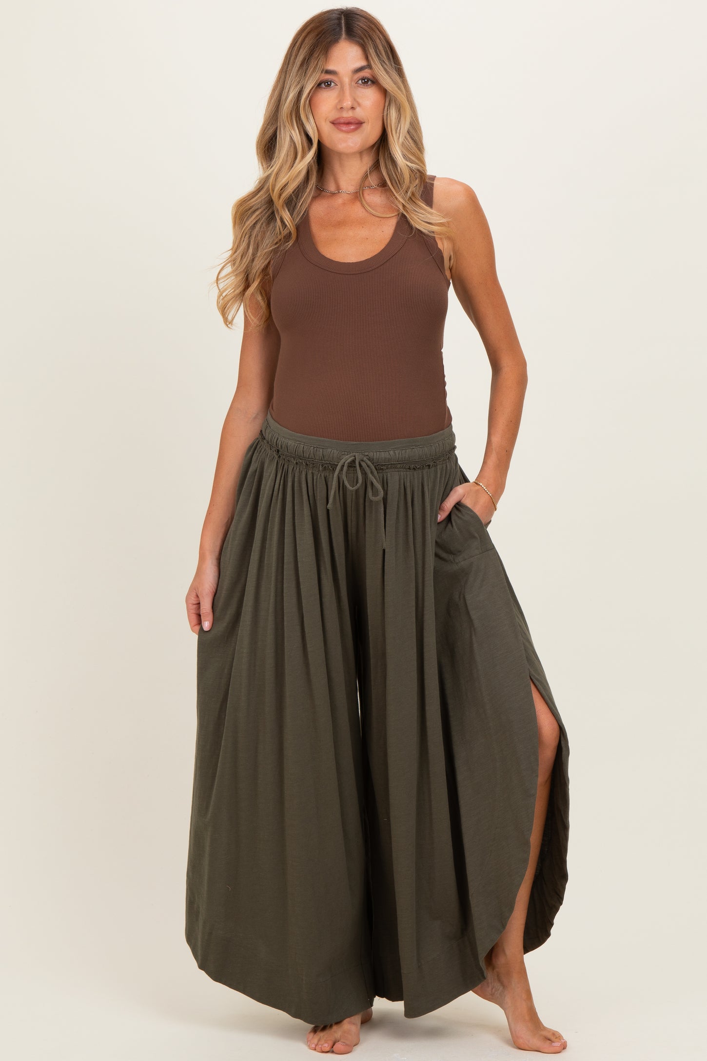 woman wearing a brown ribbed maternity tank top and olive green wide-leg maternity pants with side slits