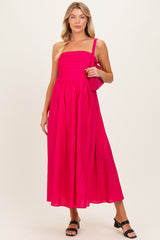woman wearing a bright pink strapless maternity dress with a pleated design and holding a matching handbag
