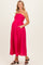 woman wearing a hot pink striped strapless maternity dress with pockets and a visible baby bump