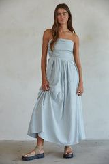 woman wearing a strapless light blue and white striped maxi dress with a fitted bodice and flowing skirt