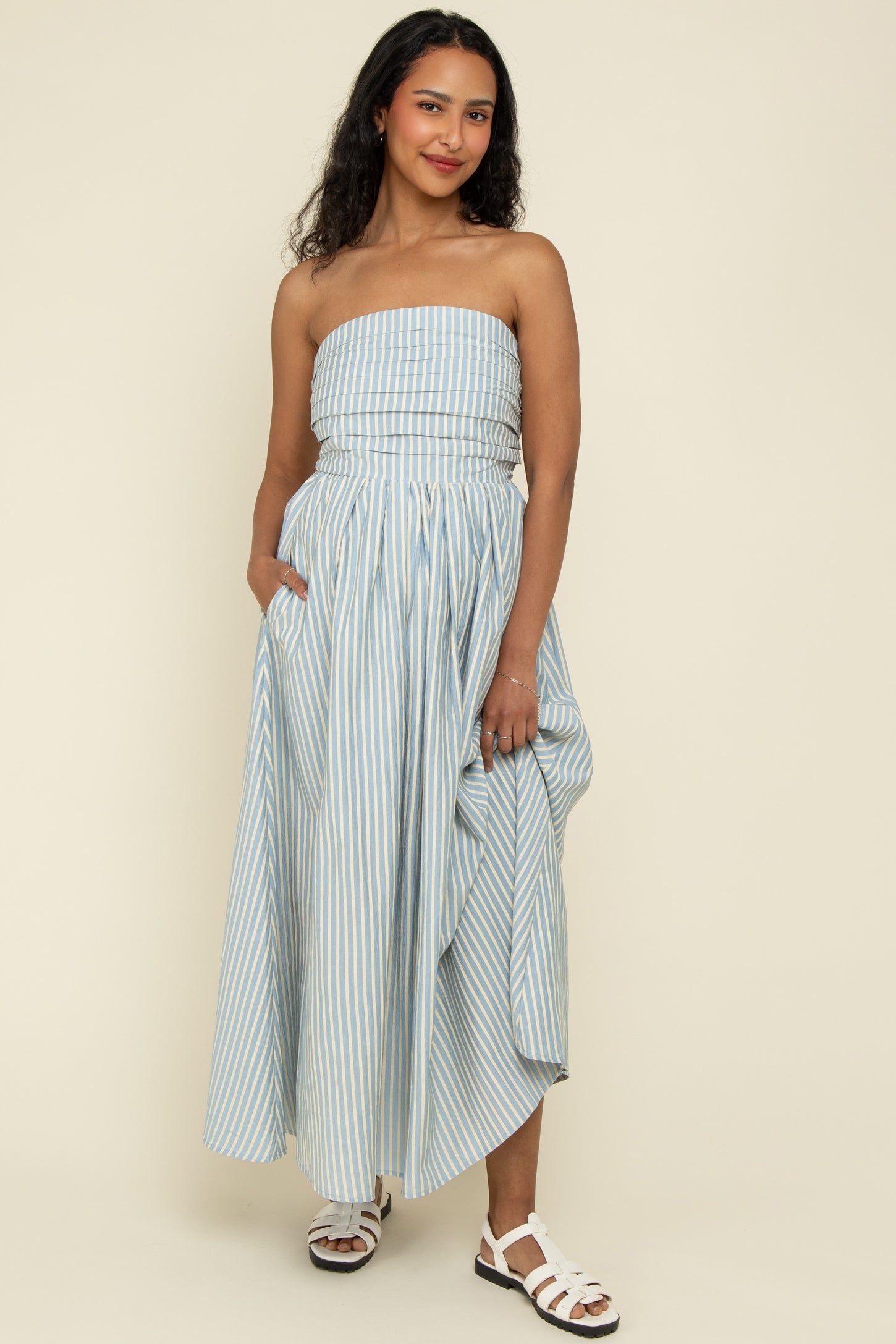 woman wearing a light blue and white striped maternity dress with a strapless top and flowing skirt