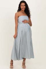 woman wearing a light blue and white striped strapless maternity dress, holding her baby bump