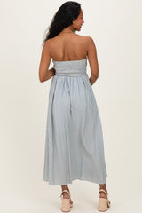 woman wearing a light blue striped strapless maternity dress with a smocked bodice and a flowy skirt, showing a baby bump