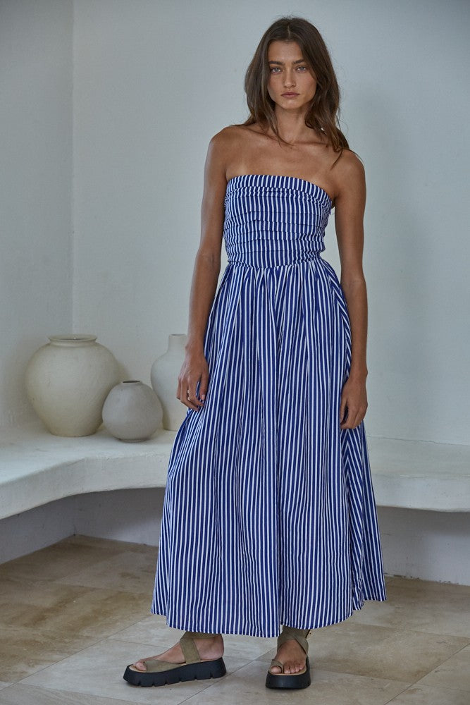 woman wearing a strapless navy and white striped maxi dress with a fitted bodice and flowing skirt
