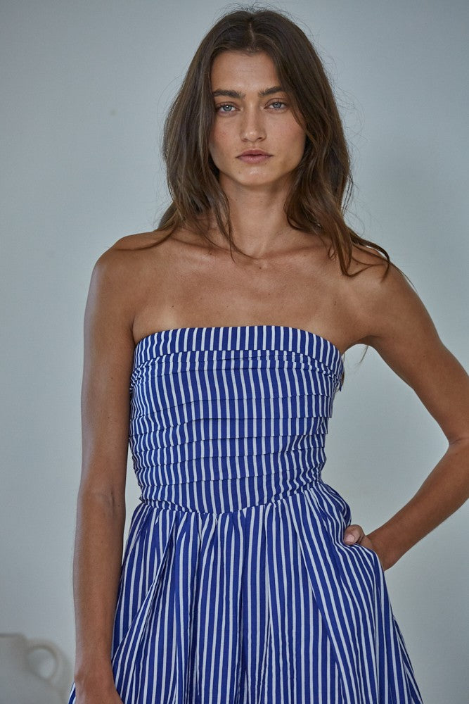 woman wearing a blue and white striped strapless maxi dress with a fitted bodice and flowy skirt