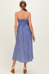 woman wearing a blue and white striped strapless maternity maxi dress, showing a fitted bodice and flowing skirt from the back