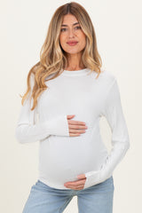 woman wearing a white long sleeve maternity top and holding her baby bump