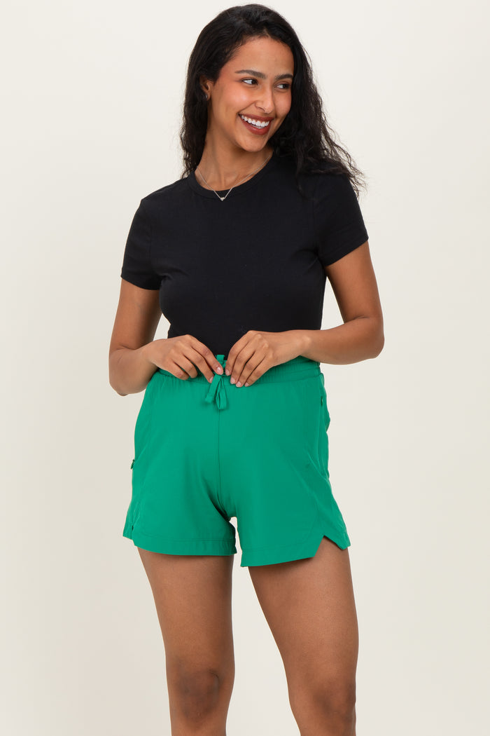 woman wearing a black short sleeve top and green maternity shorts with a drawstring waist