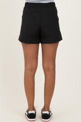 woman wearing black maternity shorts, seen from the back, showcasing a comfortable fit and elastic waistband