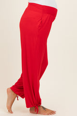 woman wearing bright red maternity pants with a stretchy waistband and tapered ankles, showcasing her baby bump