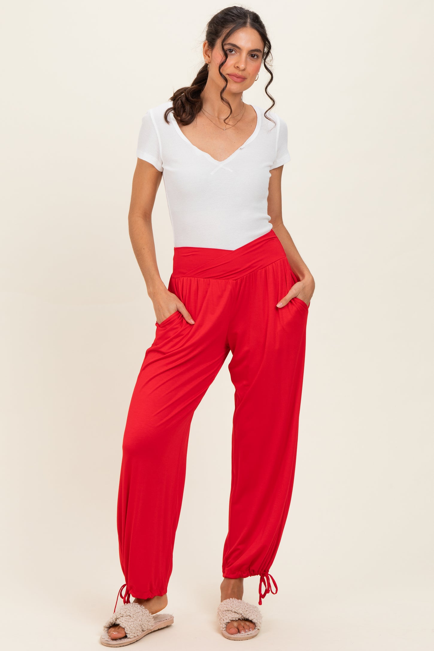 woman wearing a white short sleeve v-neck top and red jogger pants with pockets and ankle ties